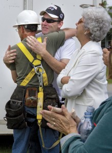 After a new church steeple was installed on Saturday, Lowell Congregational Church Pastor David Dizazzo embraces member Omer Roberge (left) in celebration.  Former Pastor John Genco’s wife, Ruth Genco, admires the steeple, and other members of the congregation clap for Mr. Roberge.  