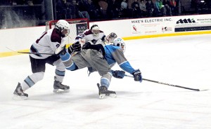 North Country Falcon Ben Pecue (left) upends South Burlington Rebel Eric Craig as Falcons' goalie Chris Bronson looks on during boys varsity hockey action at the Ice Haus in Jay on Saturday night.  Photo by Richard Creaser