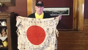 Joe Queenin of Derby Line holds up a Japanese flag, which was folded inside the helmet of the Japanese soldier he killed during the war.  The flag is covered with wishes for a safe return, hand-written by friends and family of the young soldier.   Photo by Elizabeth Trail