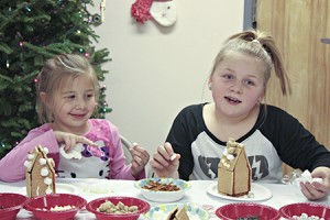 Kenzie Breitmeyer (left) and sister Brooke Breitmeyer put the finishing touches on their graham cracker houses.