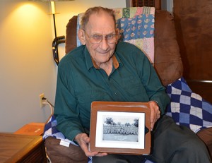 Donald Wheatley served in the Army during World War II.  Here he poses with a picture of his outfit during the war, of which he is the last living member. Photo by Nathalie Gagnon-Joseph