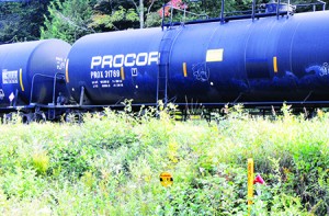 One of the hundreds of propane tank cars stored on a railroad siding south of Barton.  Although railroad officials said the cars are secure, this car has been spray-painted by local graffiti artists.  The sign in the foreground marks the location of the Portland crude oil pipeline.  Photo by Elizabeth Trail