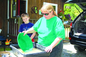 Joanne Warner of Green Mountain Prospectors demonstrates how to pan for gold.  Bryce Donahue, who said he's panned for gold dozens of times, looks on.  Photos by Tena Starr 