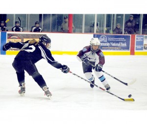 North Country's Savannah Alberghini-Giroux chips the puck past Stowe defender Katie Stames during Wednesday night's quarter final match at the Ice Haus in Jay.  Alberghini-Giroux would record one of the five goals that propelled the Falcons to a 5-0 victory over the Raiders. Photo by Richard Creaser 