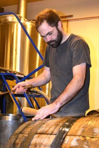 Shaun Hill works on adjusting and tightening staves on a ten-year-old oak barrel that was originally used to make bourbon.
